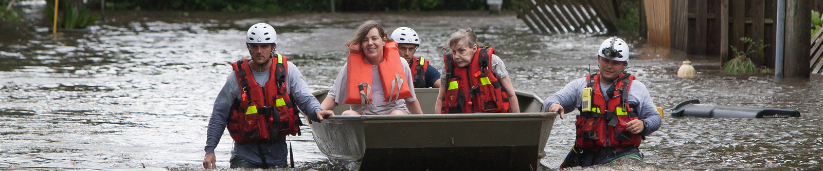 Rescuers guiding a boat with two women through deep water